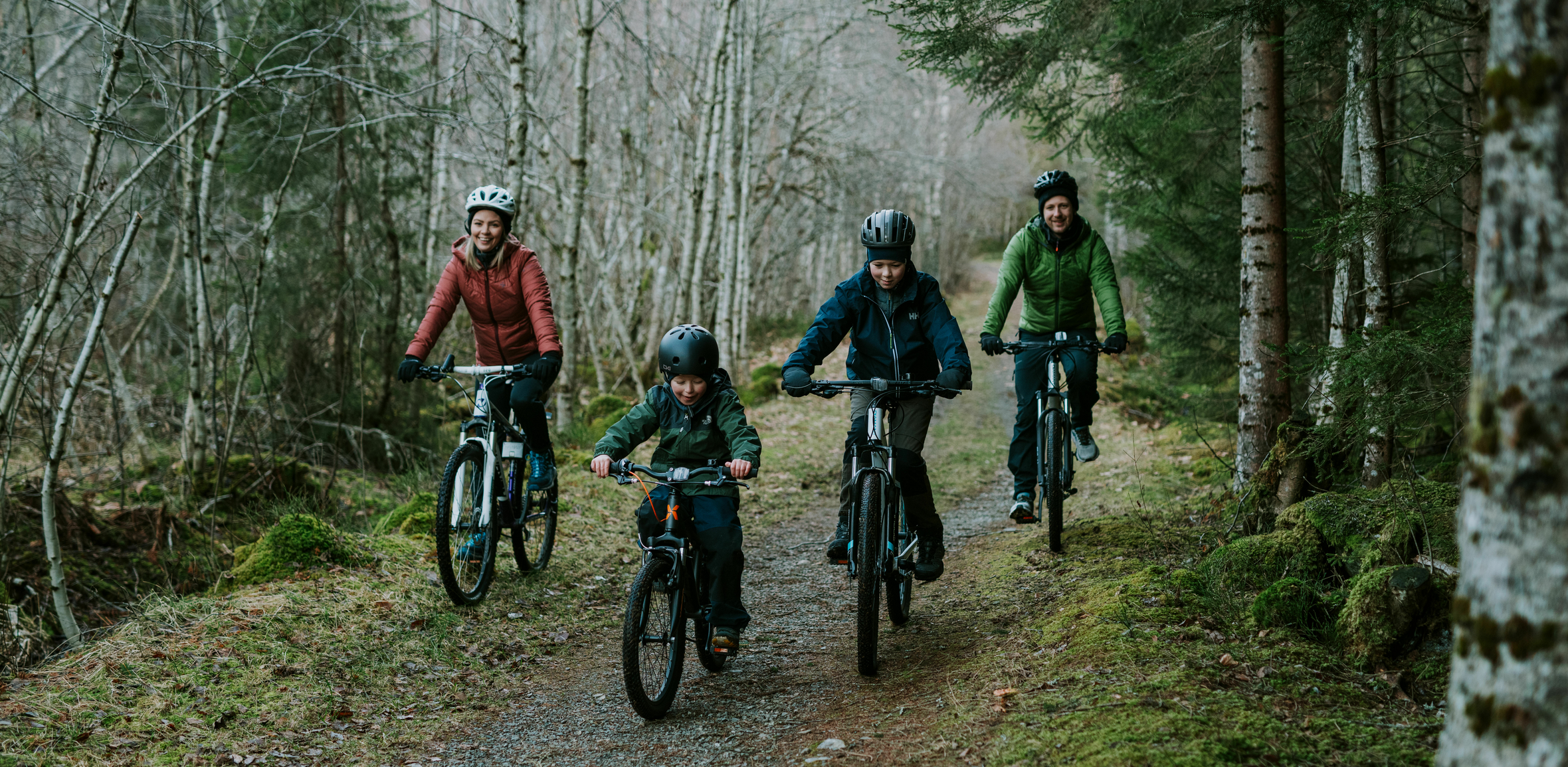 Familie på 4 sykler på en skogsvei